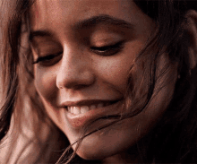 a close up of a woman 's face with her eyes closed and her hair blowing in the wind