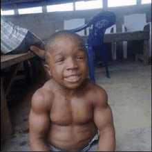 a shirtless young boy with muscles is sitting on the ground .