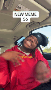 a man wearing a red sweatshirt with the number 56 on it is sitting in a car