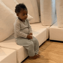 a little boy is sitting on a white couch holding a toy