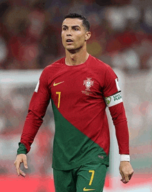 a soccer player wearing a red and green jersey with the number 7 on it .