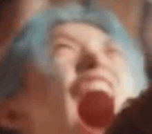 a person with blue hair is screaming with their mouth open .