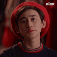 a young boy wearing a red beret and a black shirt with the nick logo on the bottom