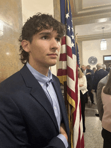 a man in a blue suit stands in front of an american flag