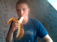 a man wearing a blue shirt with the word ny on it eating a banana