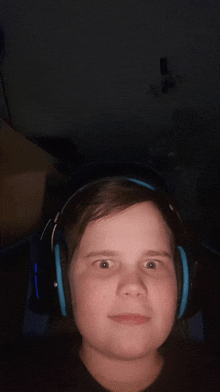 a young boy wearing headphones looks at the camera in a dark room