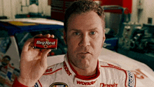 a man in a race car uniform is holding a box of big red