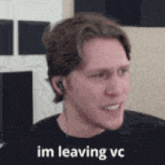 a man wearing headphones and a black shirt is smiling and says `` im leaving vc '' .