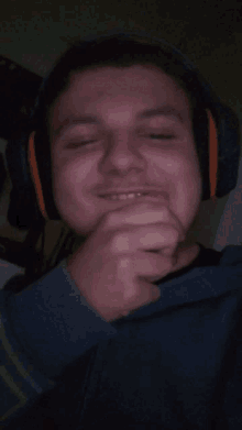 a man wearing headphones is smiling and covering his mouth with his hand