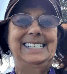 a woman wearing sunglasses and a hat is smiling for the camera