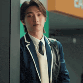 a man in a suit and tie leans against a door