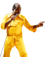 a bald man in a yellow jumpsuit sings into a microphone