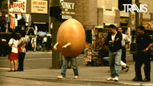 a man in a large egg costume is walking down a street in front of a sign that says leed import