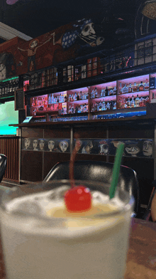 a drink with a cherry in it sits on a table in a bar