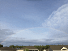 a rainbow is visible in the sky over a row of houses