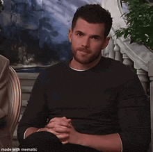 a man is sitting in a chair with his eyes closed and his hands folded
