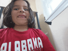 a young girl wearing a red alabama shirt