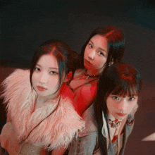 three girls are posing for a picture and one has a fur coat on