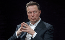 a man in a suit and white shirt holds his hands together