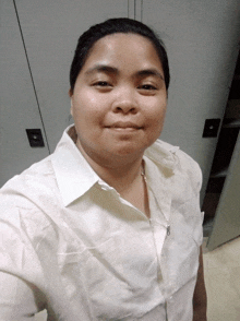 a woman wearing a white shirt and a necklace smiles for the camera