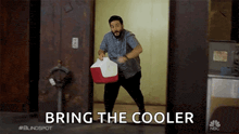 a man is carrying a red and white cooler with the words bring the cooler below him