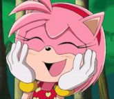 amy rose from sonic the hedgehog is smiling and holding her face with her hands