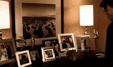 a man is standing in front of a table with a bunch of framed pictures on it .