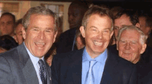 two men in suits and ties are smiling for a picture .