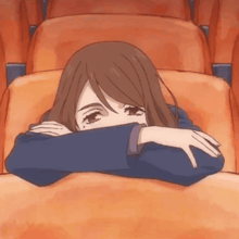 a girl covering her face with her hand while sitting in a chair