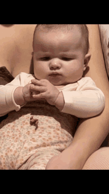 a baby is being held in a woman 's arms and looks at the camera