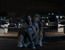 a man and a woman are sitting on a bridge at night