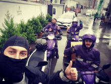 a man wearing a mask gives a thumbs up while riding a motorcycle