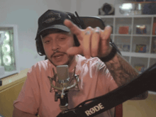 a man wearing headphones and a rode microphone giving a thumbs up