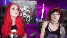 two women with red hair are sitting in front of a sign that says " dark hay "