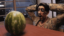 a man with an eye patch is sitting at a table with a watermelon on it .