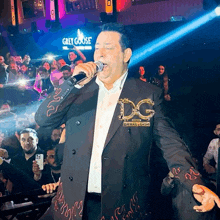 a man singing into a microphone with a grey goose sign behind him