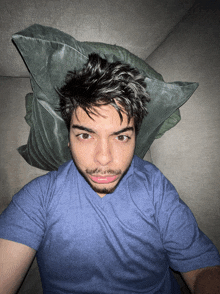 a man laying on a couch with a green pillow on his head