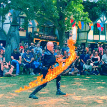 a man is holding a sword of fire in front of a crowd of people in front of a building that says robertson center