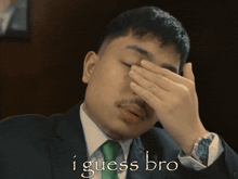 a man in a suit and tie covering his face with his hand with the words i guess bro written below him
