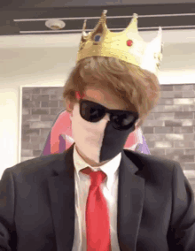 a man in a suit and tie is wearing a crown and sunglasses