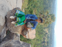 a man sitting on a rock wearing a green skirt and adidas shoes