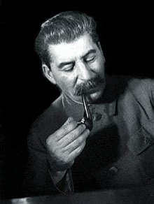 a man is smoking a pipe in a black and white photo .