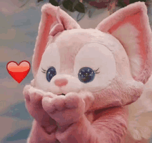 a stuffed animal in a pink and white costume with a red heart behind it .