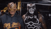 a man wearing a hoodie that says rey fenix stands next to another man in a mask
