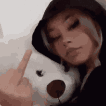 a woman is holding a stuffed animal and giving the middle finger .