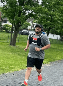 a man is running down a path wearing headphones and a backpack .