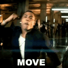 a man in a black jacket is dancing in a hallway with the word move written on the screen .