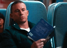 a man is reading a book while sitting on a bus .