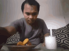 a man sitting on a couch with a plate of food and a glass of milk with a spoon in it