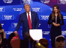 a man in a suit and tie stands next to a woman in front of a wall that says trump vance